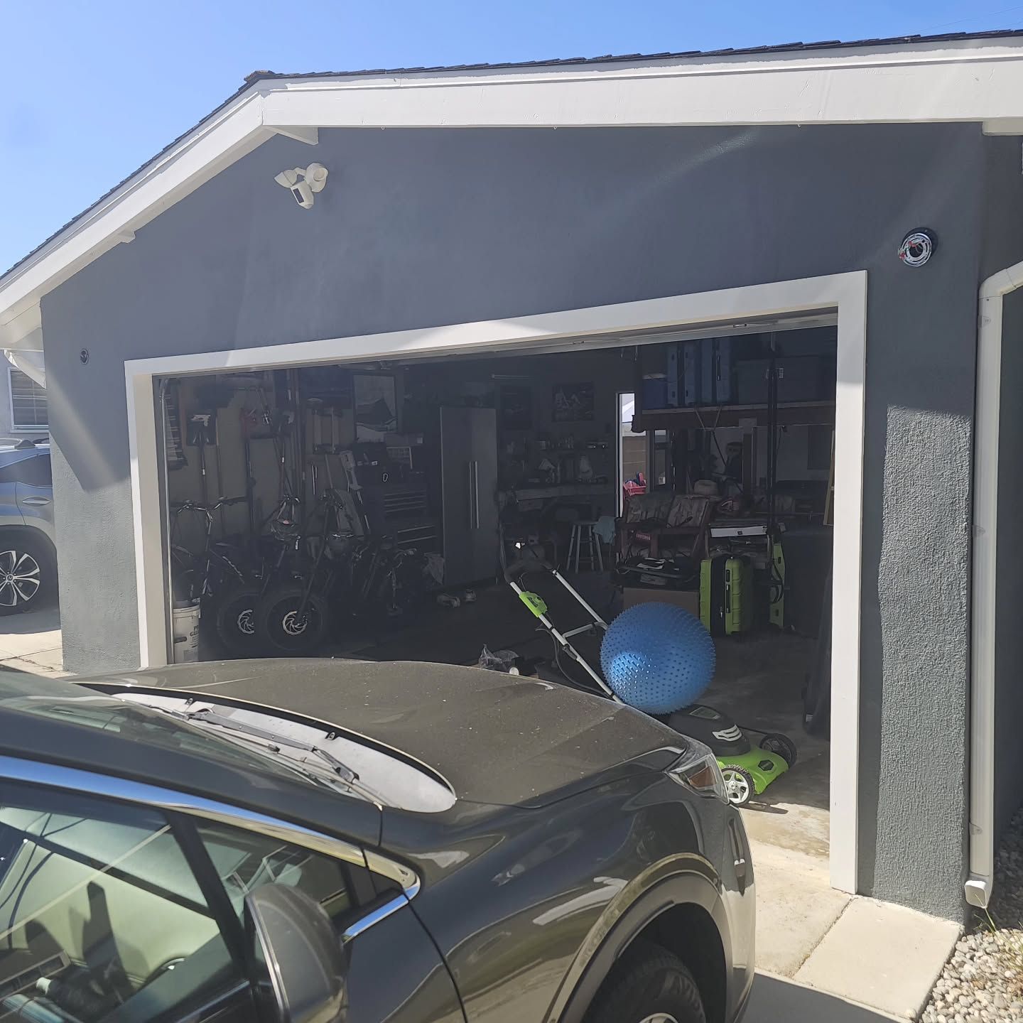 Gray garage with white trim; a car in front; interior visible with items stored inside.