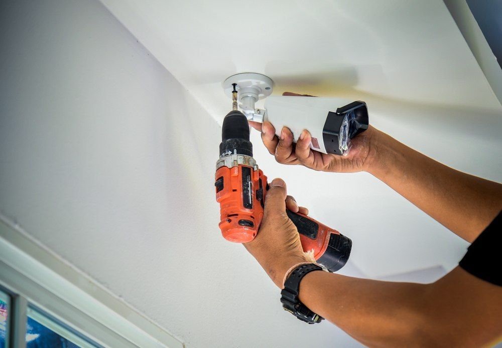Person Using a Drill to Install a Fixture — X-Mod Security In Landsborough, QLD