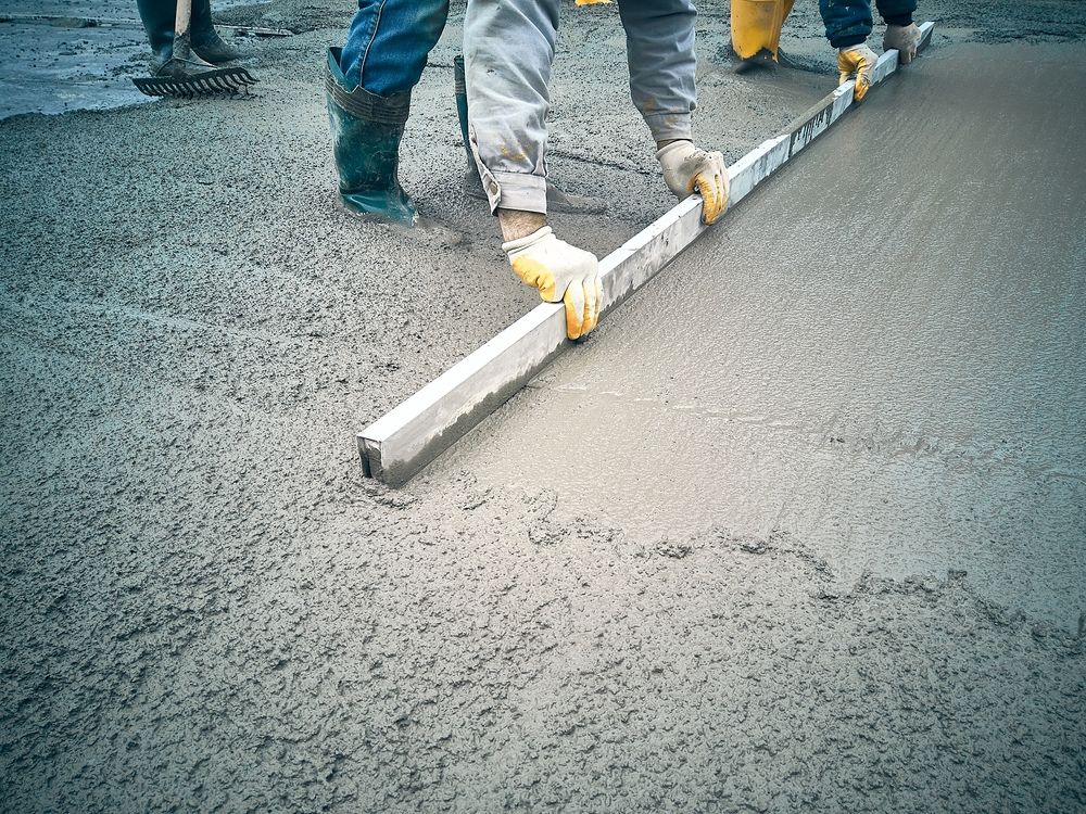 A Man Is Kneeling Down And Using A Trowel On A Concrete — Lonnie Henderson Concreting In Dubbo, NSW