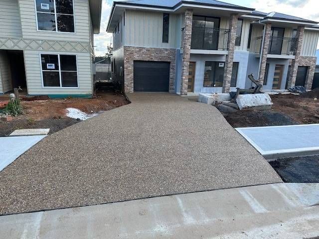 A Gated Driveway Leading To A House With Trees In The Background — Lonnie Henderson Concreting In Dubbo, NSW