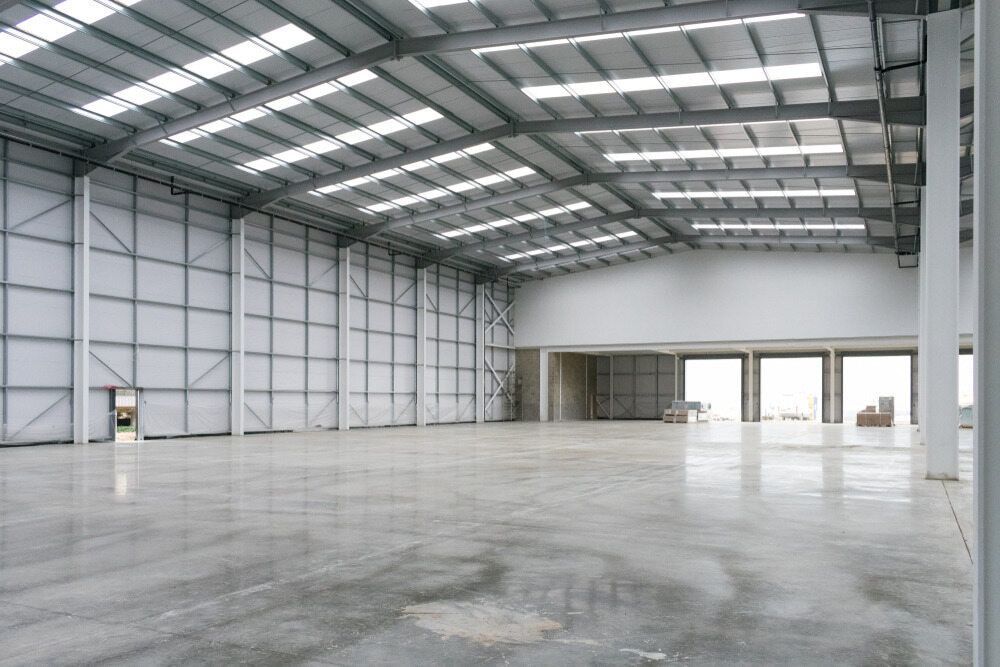 A Large Empty Warehouse With A Concrete Floor — Lonnie Henderson Concreting In Forbes, NSW