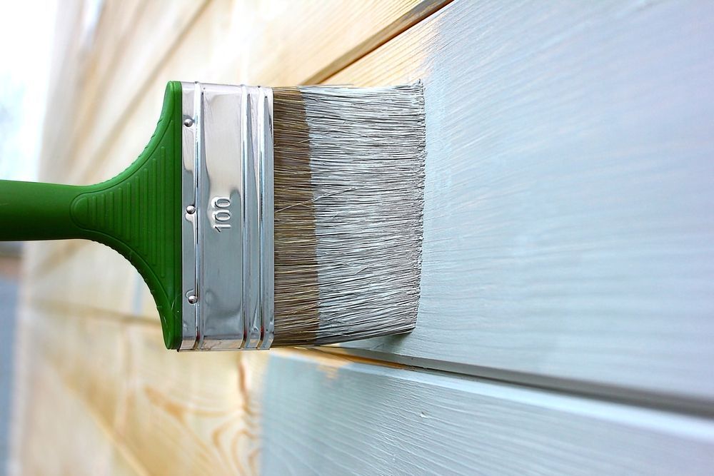 Paint Brush Applying Light Blue Paint to Wooden Siding — Israel Jones Painting in Rowes Bay, QLD