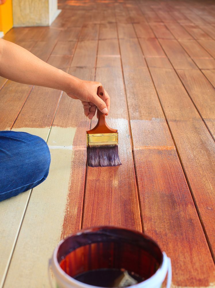 Person Applying Stain to Wooden Floor With a Paintbrush — Israel Jones Painting in Pallarenda, QLD