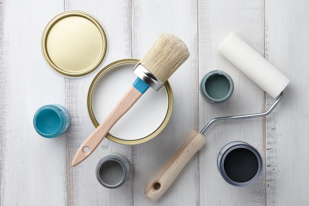 Paint Cans, Brush, and Roller on a White Wood Surface — Israel Jones Painting in Idalia, QLD
