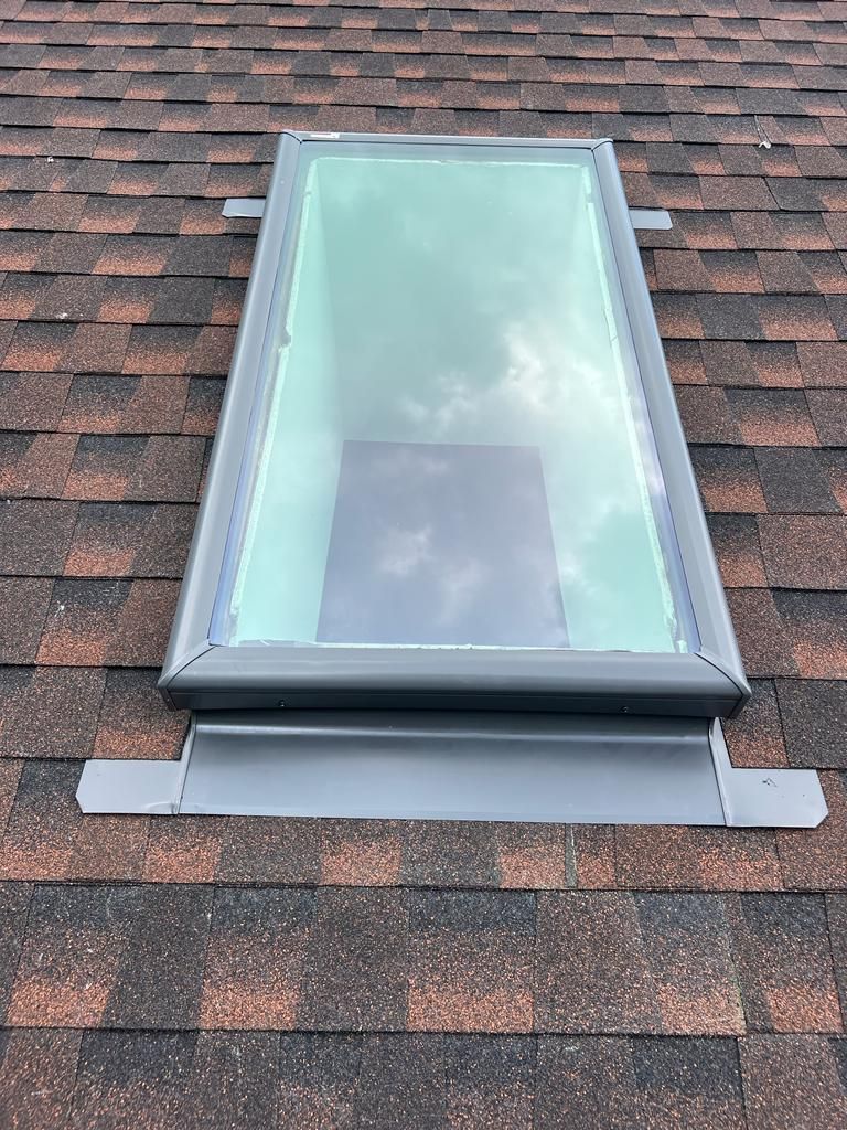 Roof skylight with frosted glass and gray flashing on asphalt shingles