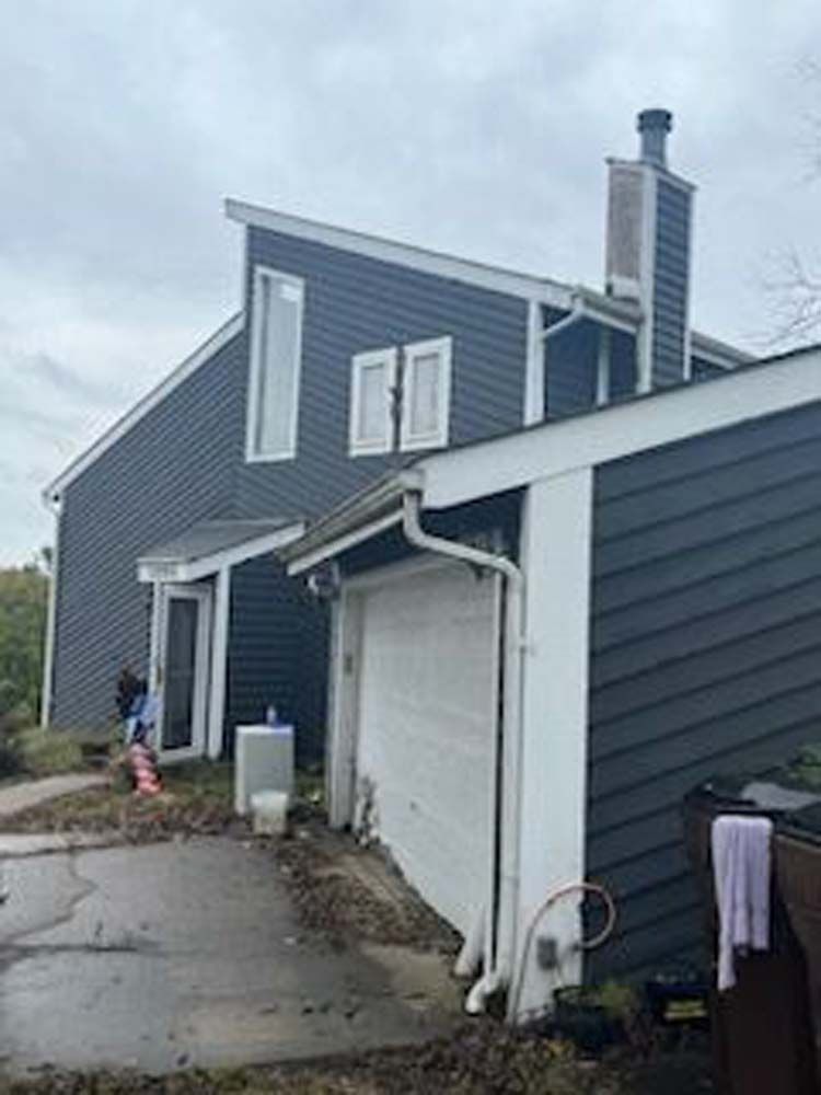 A house with a garage and a chimney on the side of it.