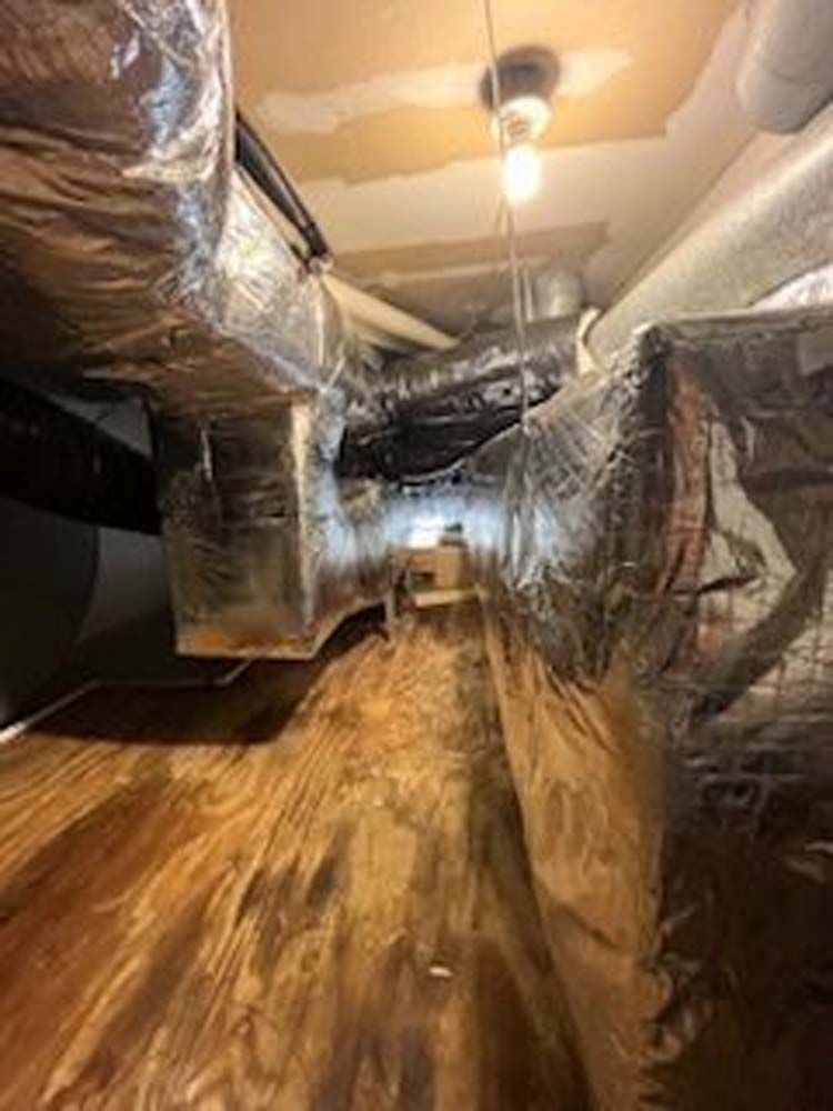 A room with a lot of ducts and a light on the ceiling.