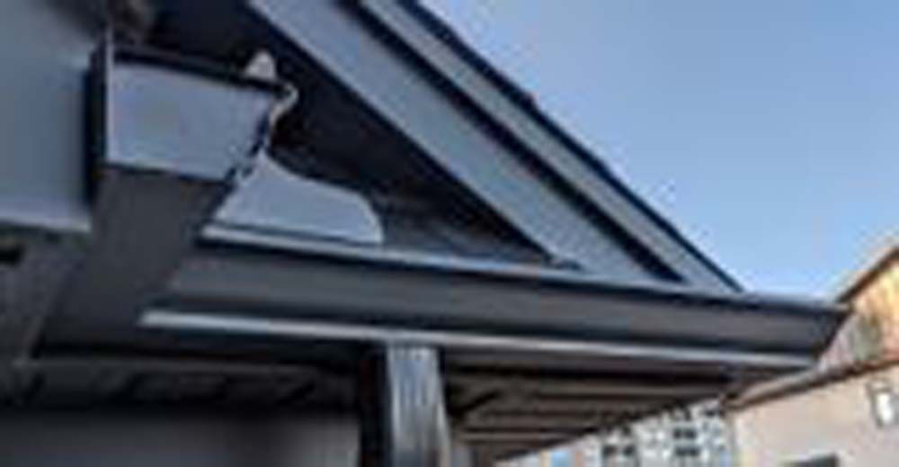 A close up of a gutter on the side of a building.