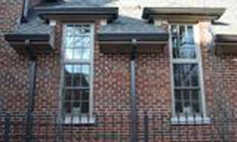 A brick building with three windows on the side of it.