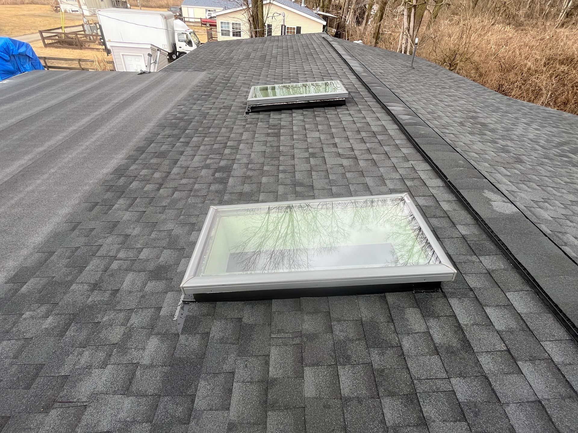 Black shingle roof with two skylights in a residential area