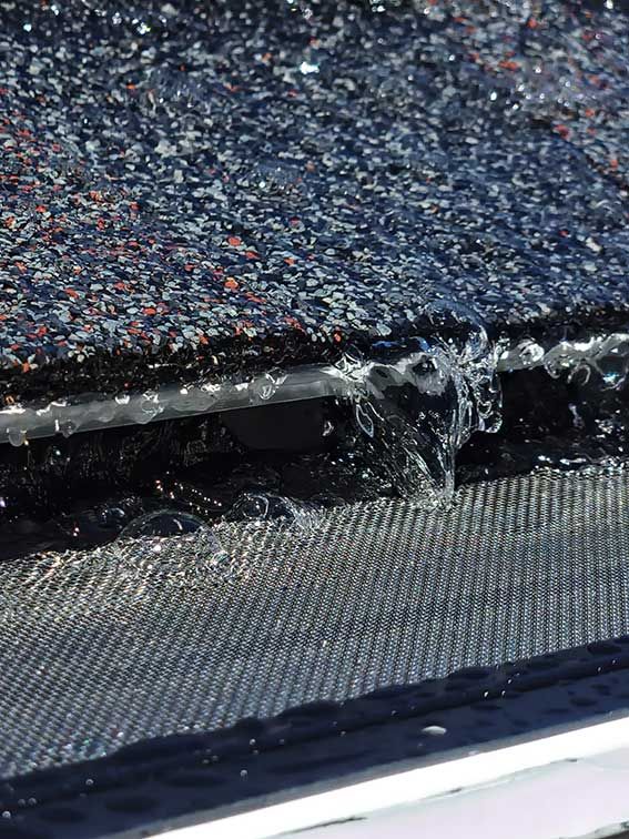 Close-up of a torn black fabric seam with frayed threads and a silver mesh edge.