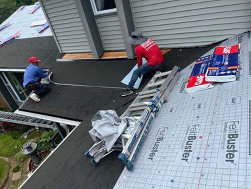 Two men are working on the roof of a house.