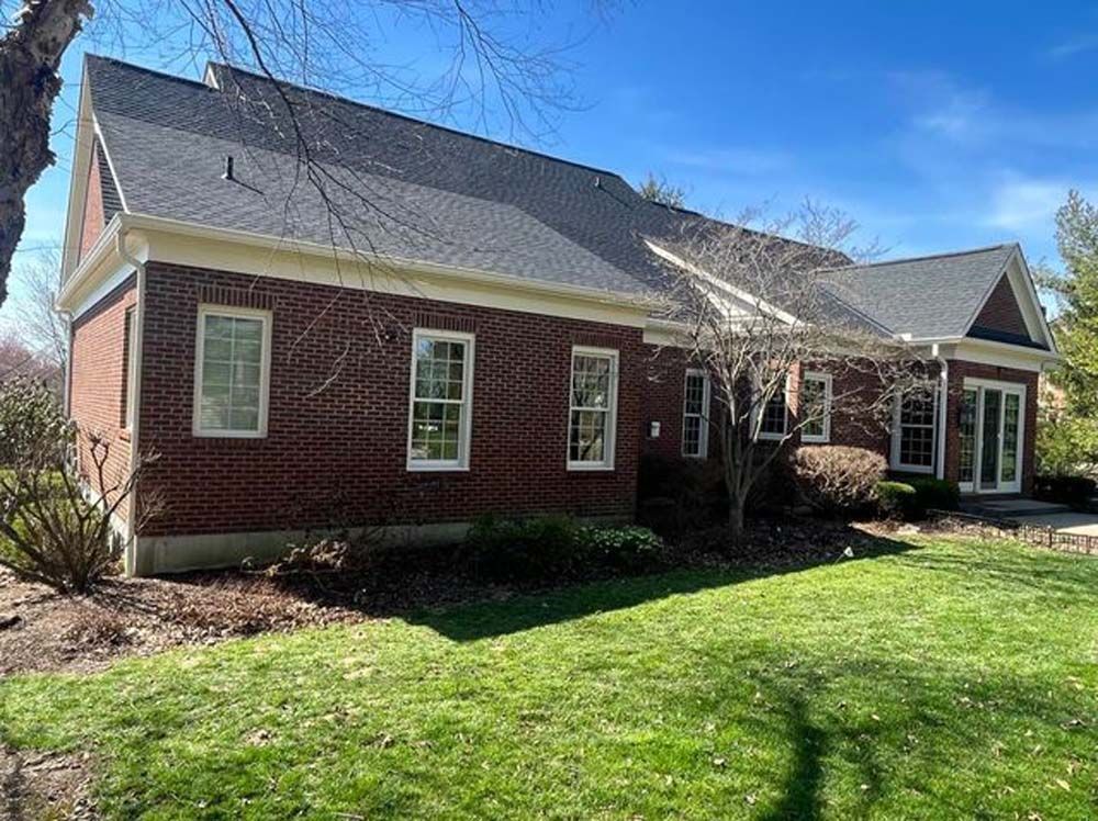 A large brick house with a large lawn in front of it.
