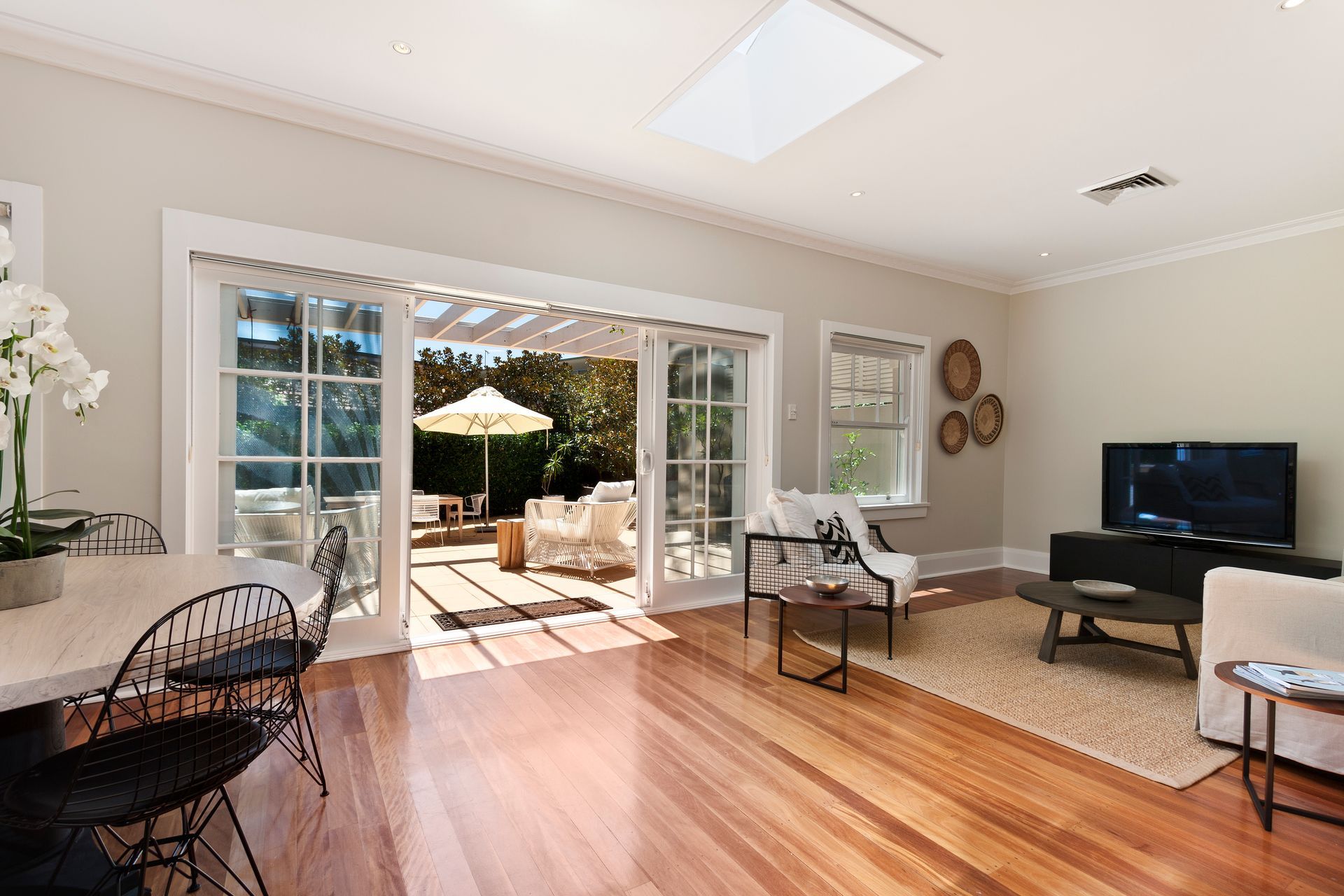 Living room with open doors to a patio. Hardwood floors, light-colored walls.