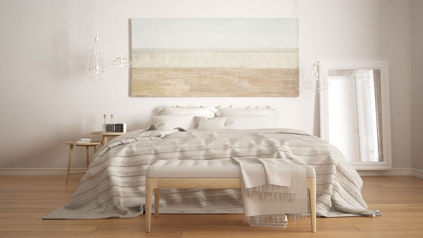 Bright minimalist bedroom with an unmade bed, neutral decor, and a large abstract wall painting.