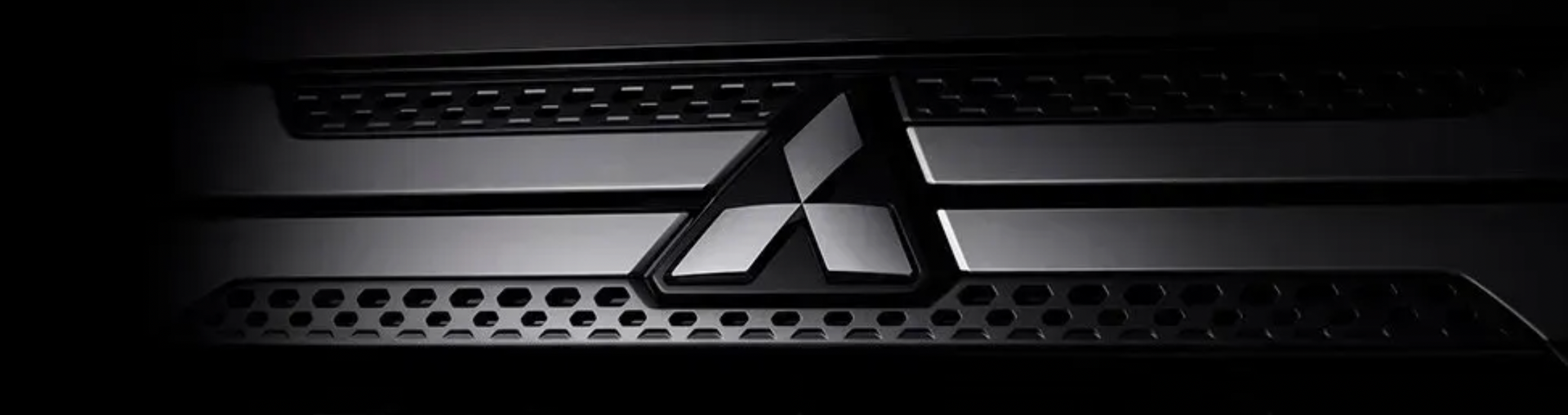 Close-up da tampa de um laptop preto com um emblema prateado da Mitsubishi.