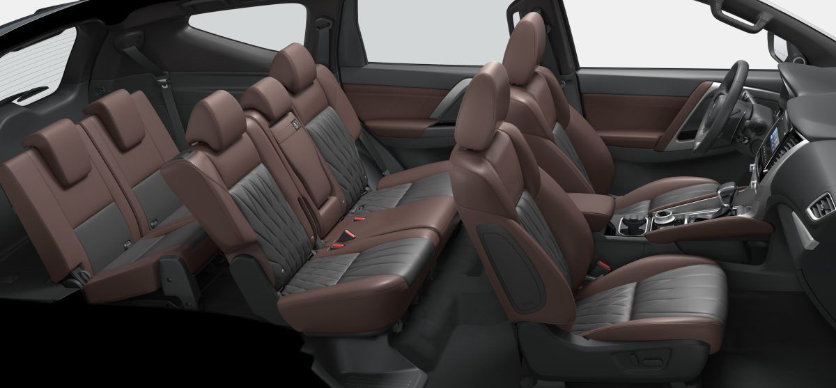 Interior de um SUV moderno com três fileiras de bancos de couro marrom e preto.
