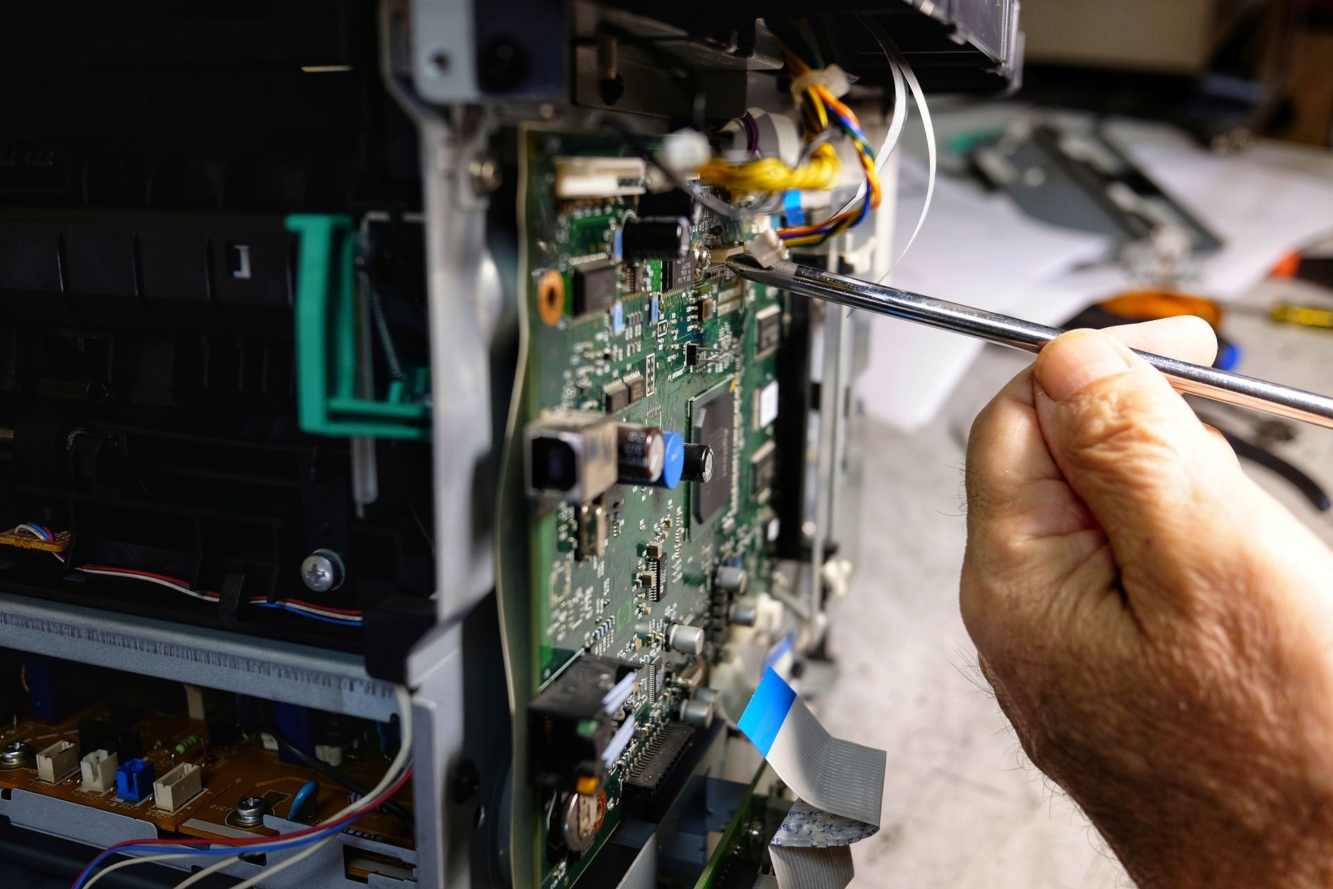 A technician is repairing a photocopier with a screwdriver