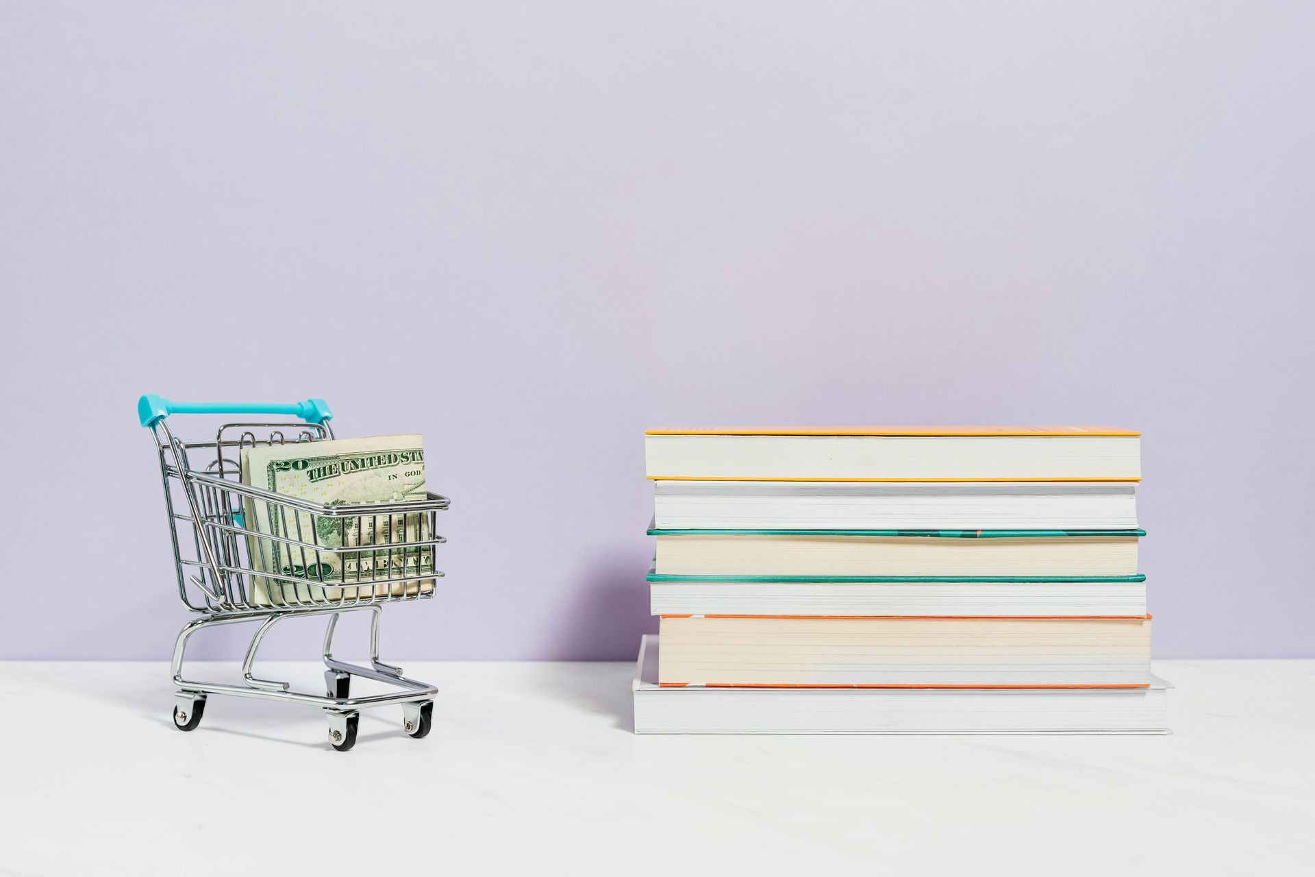 A shopping cart full of money and a stack of books next to it.