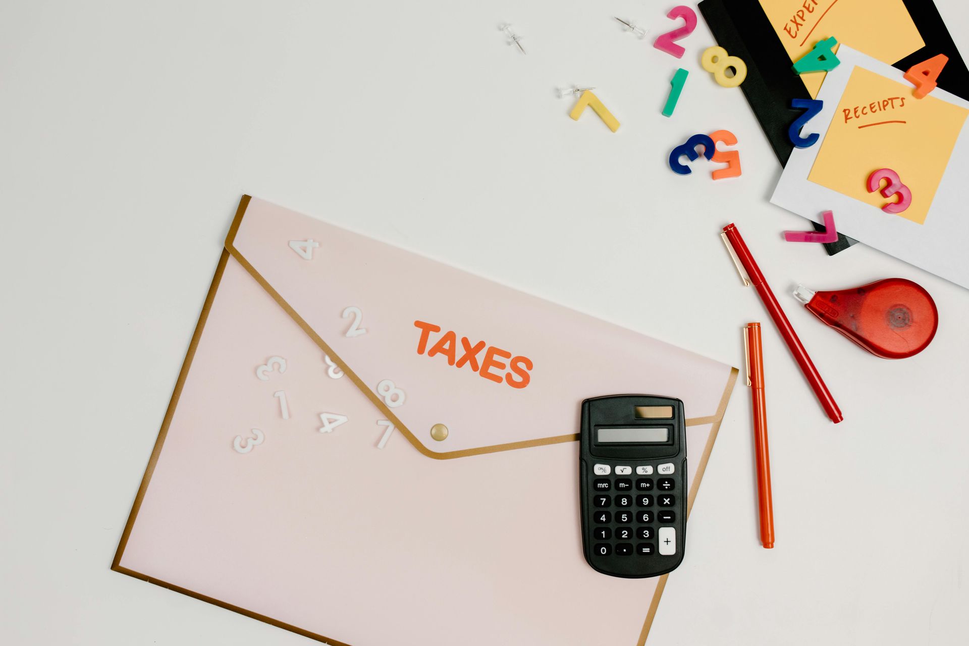 A folder labeled taxes on it with a calculator and pencils by it.