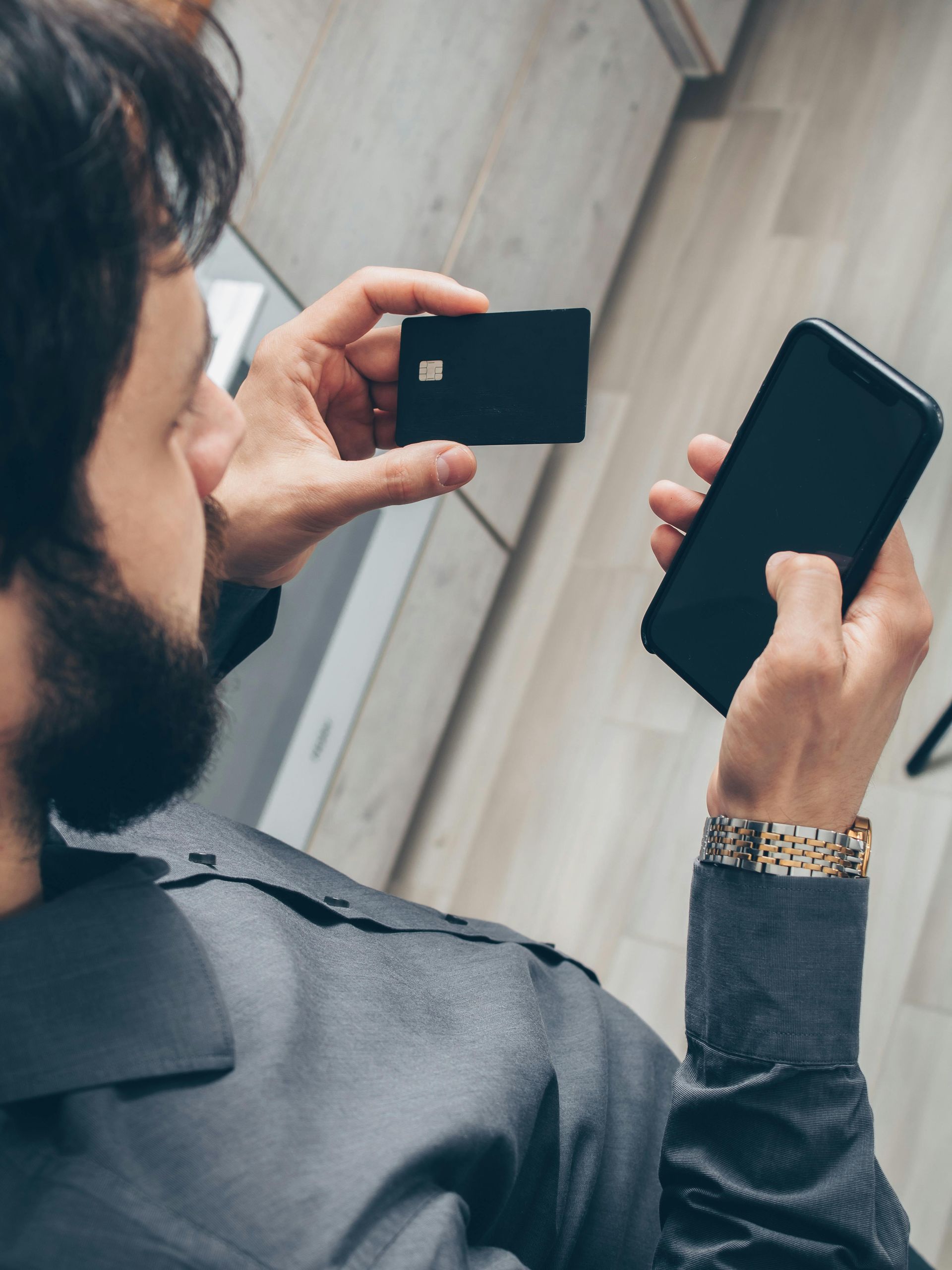 A man holding his phone and debit card.