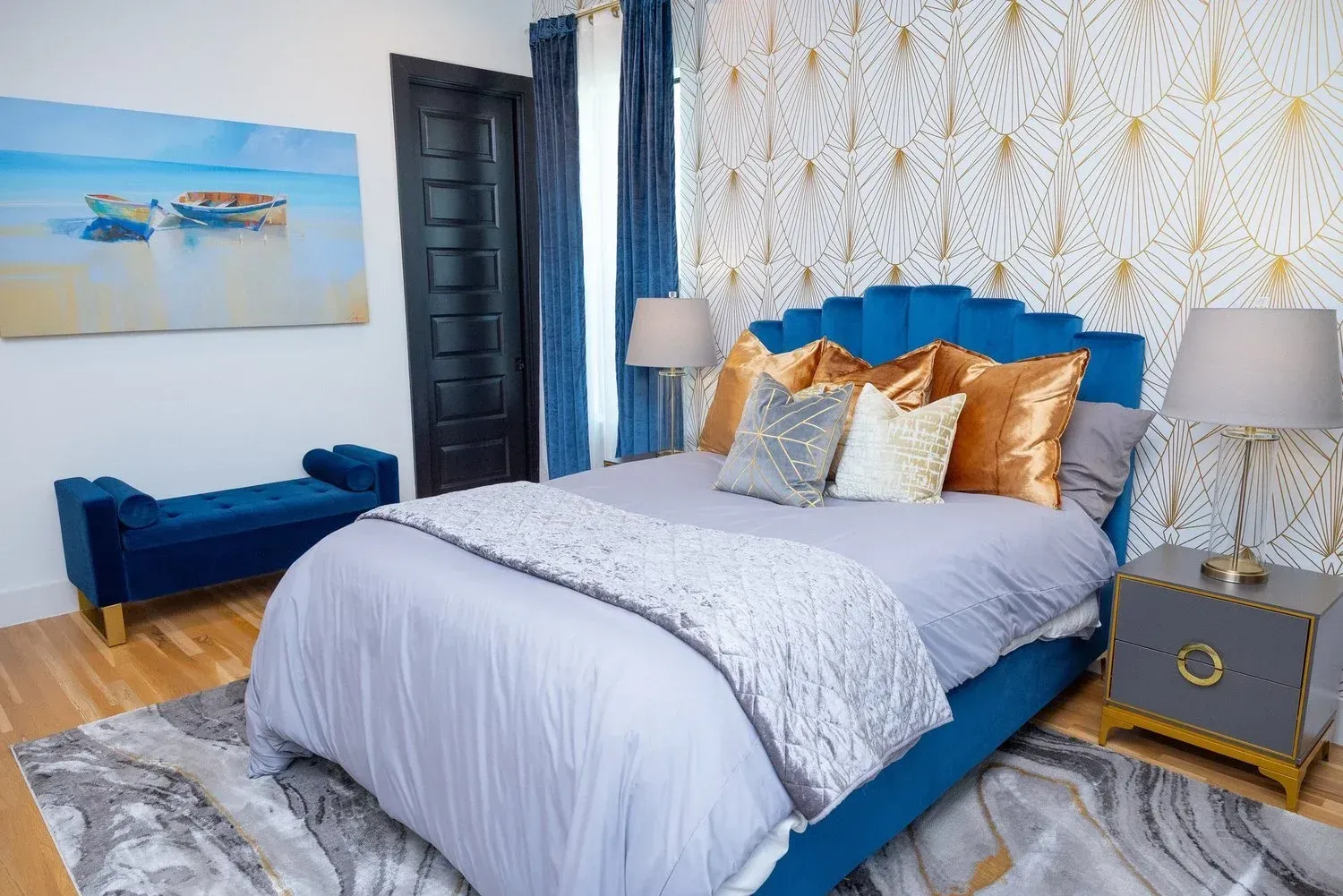 A blue bed with gold accents and a white textured wall in a bedroom with a blue bench and matching decor.
