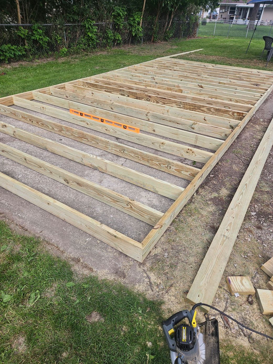 Raised garden bed with rows of wooden slats, bordered by concrete and grass outdoors.