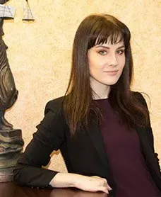 A woman is sitting at a table in front of a statue of justice.