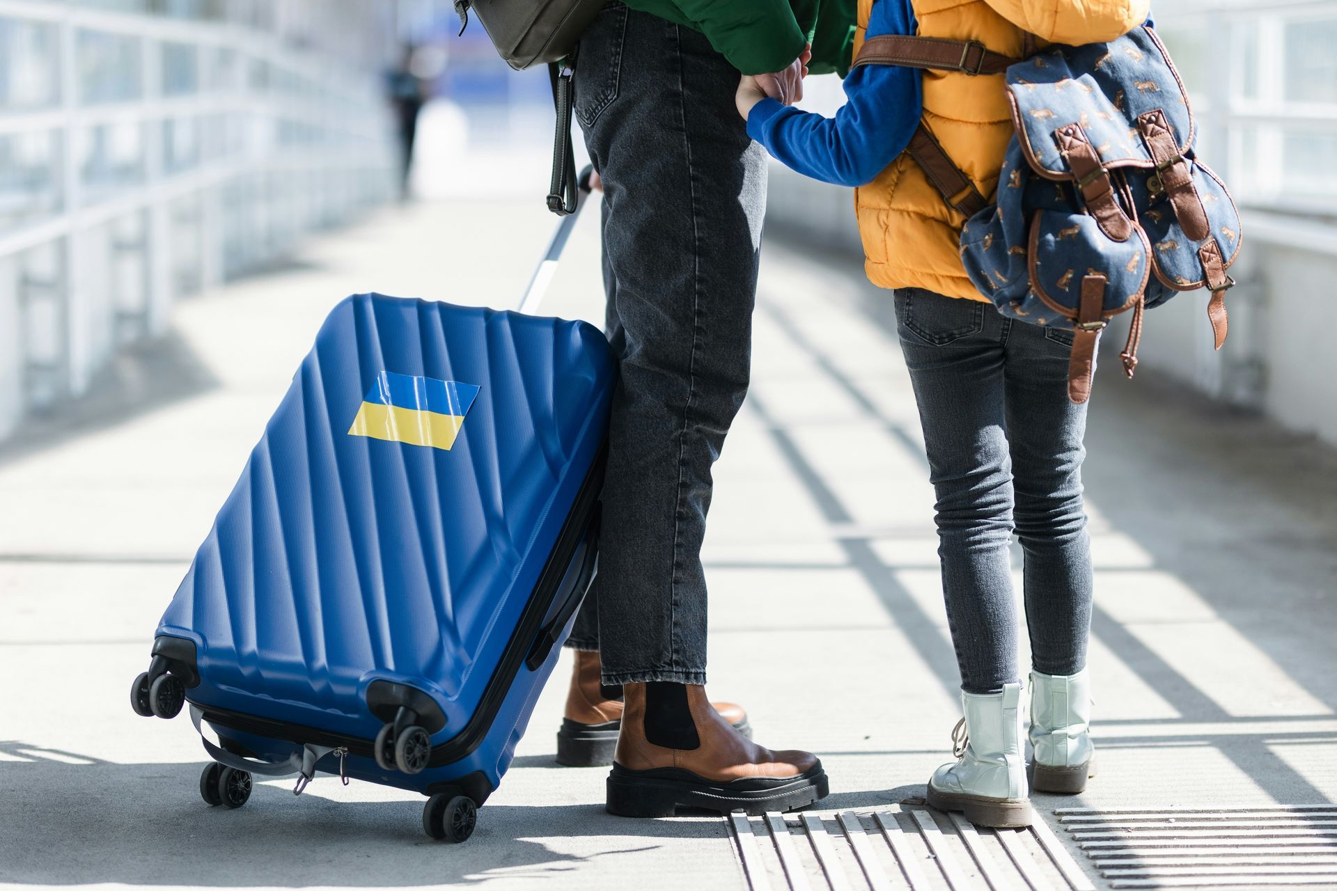A man and a child are standing next to a blue suitcase.