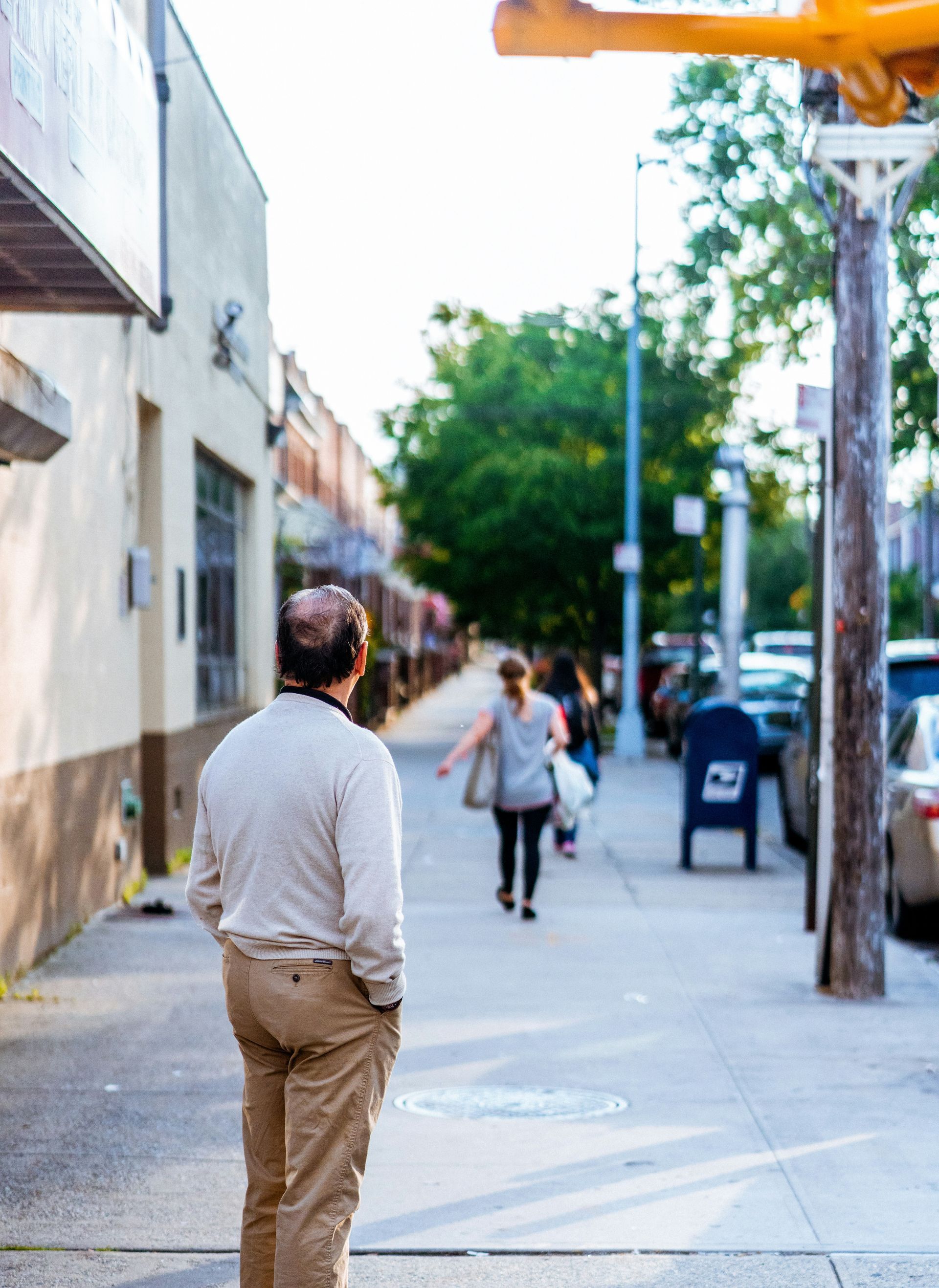 A man walking down a street with a mailbox that has the letter b on it
