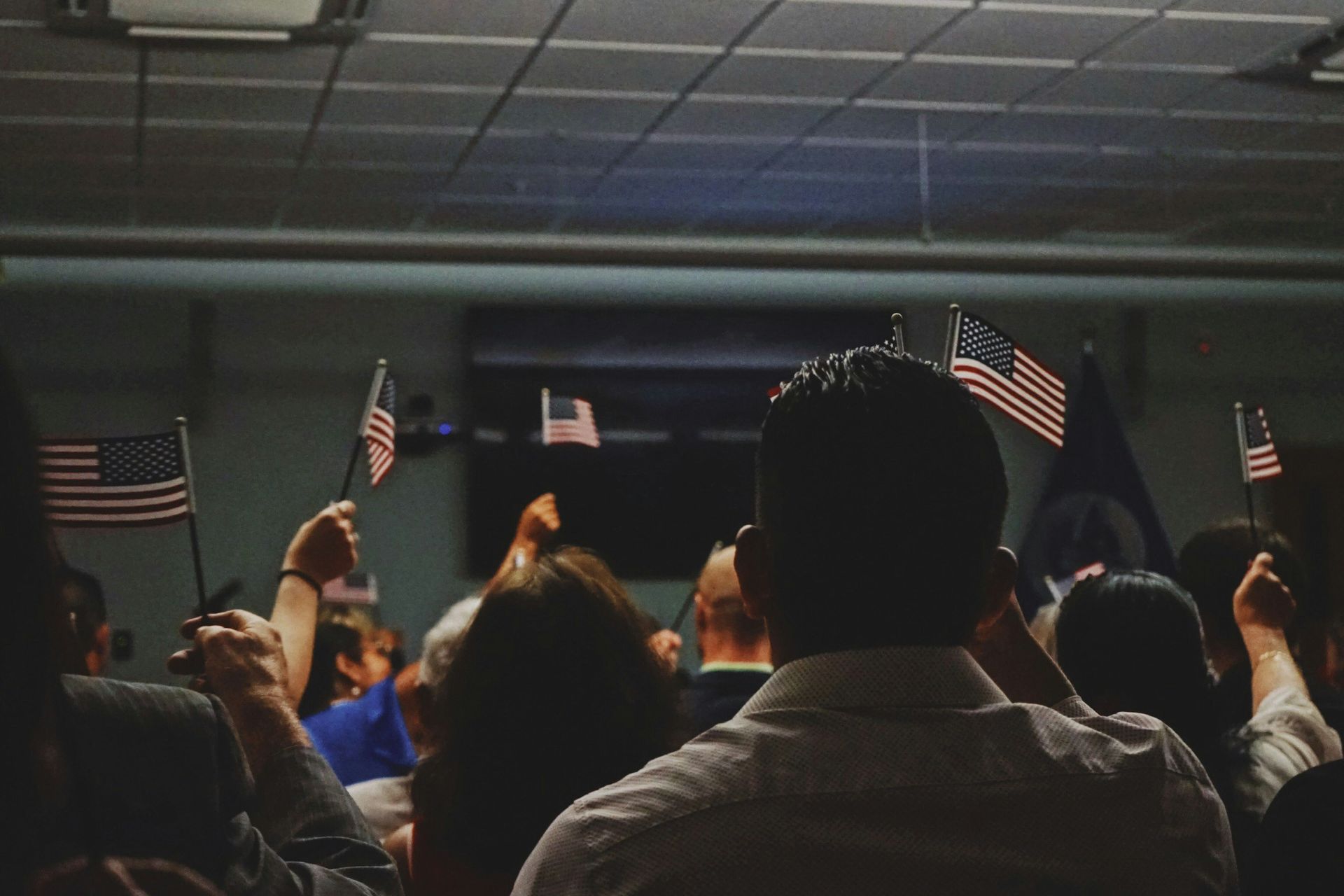 A crowd of people holding american flags in a dark room