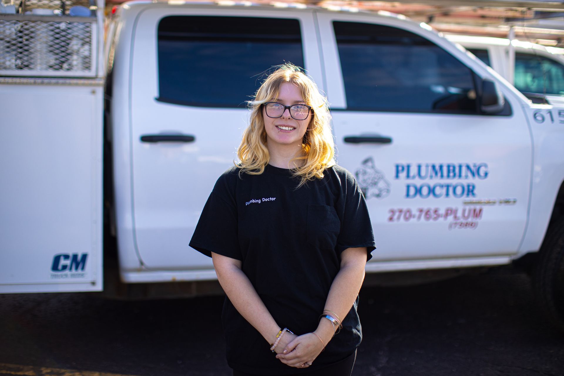 Woman in black shirt stands in front of a white truck with 