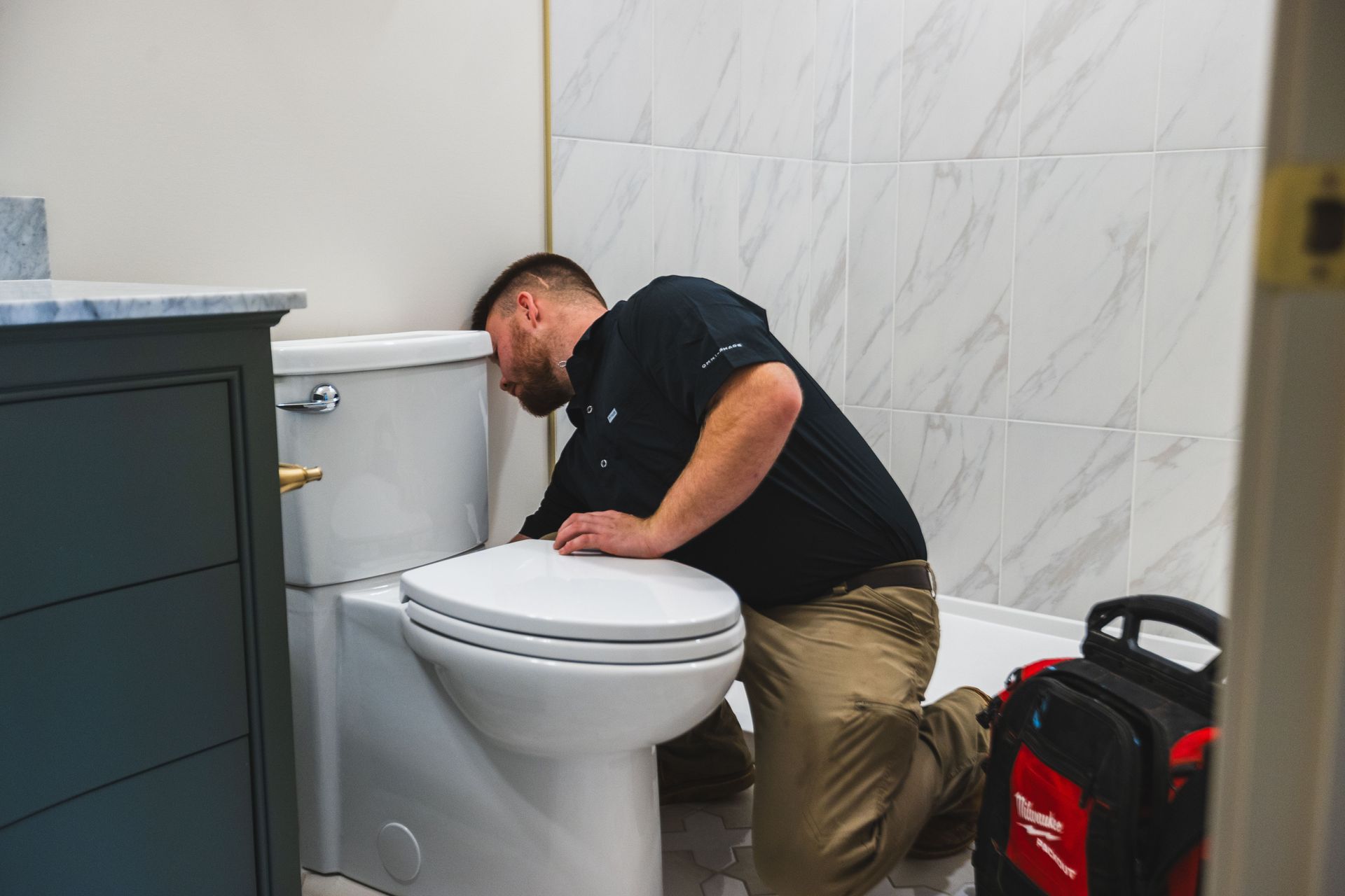 A plumber working on a toilet repair project.