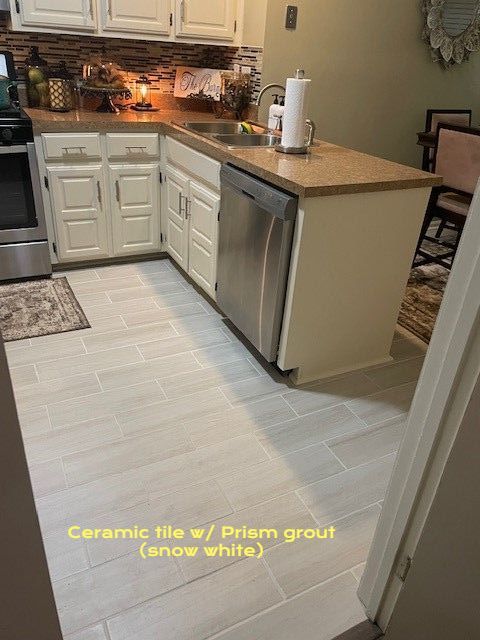 Kitchen with light wood-look ceramic tile floor, white cabinets, and stainless steel dishwasher.