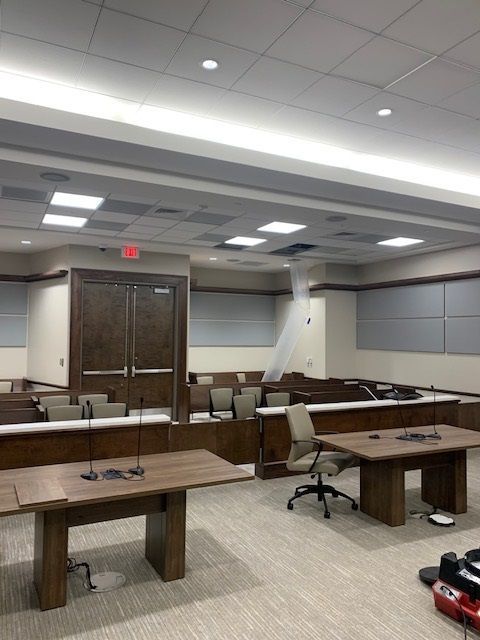 A conference room with tables and chairs and a red exit sign