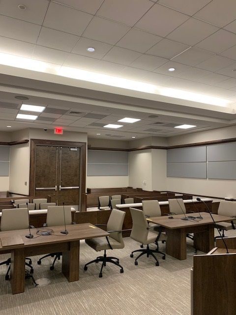 A conference room with tables and chairs and a red exit sign