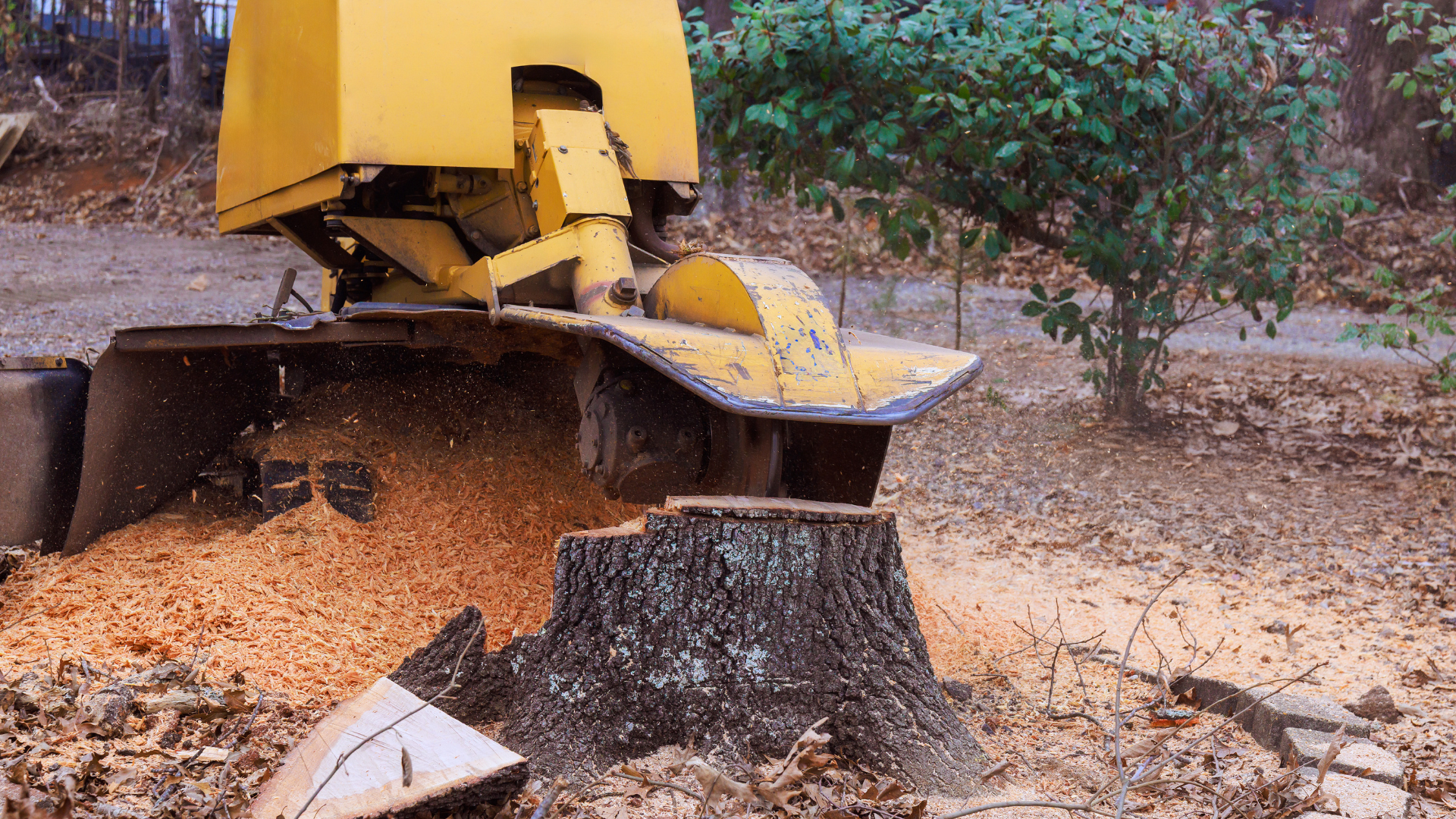 Yellow excavator unloading orange gravel into a black container outdoors on a dirt lot.