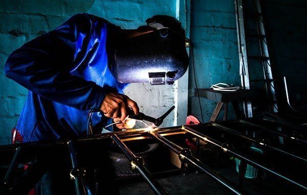 Arafed Man Welding Metal in a Workshop With a Blue Background — AWE Engineering in South Lismore, NSW