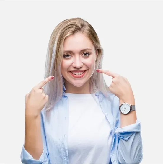 Smiling person in a light blue shirt pointing at their cheeks against a white background