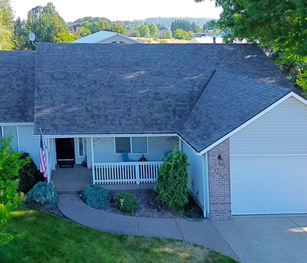 An aerial view of a house with a gray roof and a porch.