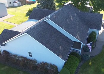 An aerial view of a white house with a black roof.