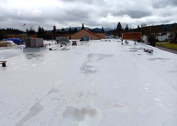 The roof of a building is covered in snow on a cloudy day.