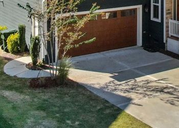 An aerial view of a house with a concrete driveway and a wooden garage door.