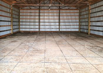 A large empty barn with a tiled floor and wooden walls.