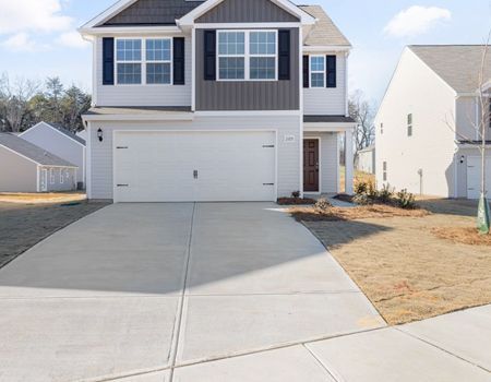 Suburban two-story house with gray siding, white trim, and a wide concrete driveway
