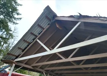 A carport with a roof that has been damaged by a storm.