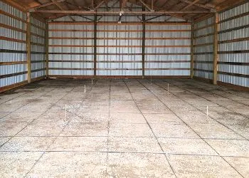 An empty barn with a tiled floor and wooden walls.