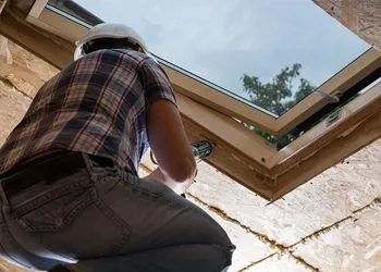 A man in a hard hat is working on a skylight.