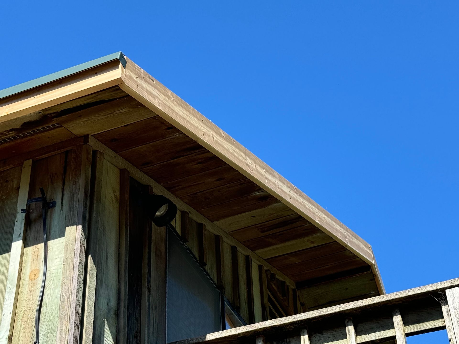 The roof of a wooden building with a blue sky in the background.