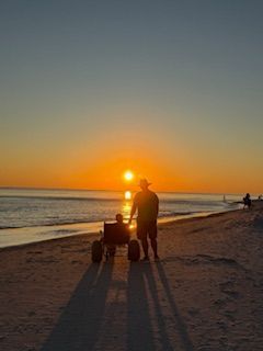 Daughter in Beach Wheelchair enjoying Sunset with her dad at Gulf Shores, Alabama